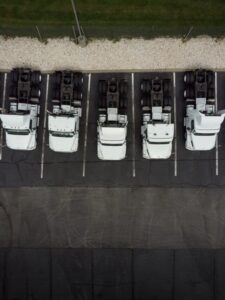 Fleet of white 18-wheeler semi-trucks overhead view drone photog