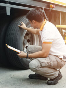 Truck driver holding clipboard inspecting safety check a truck tires, vehicle maintenance checklist a semi truck